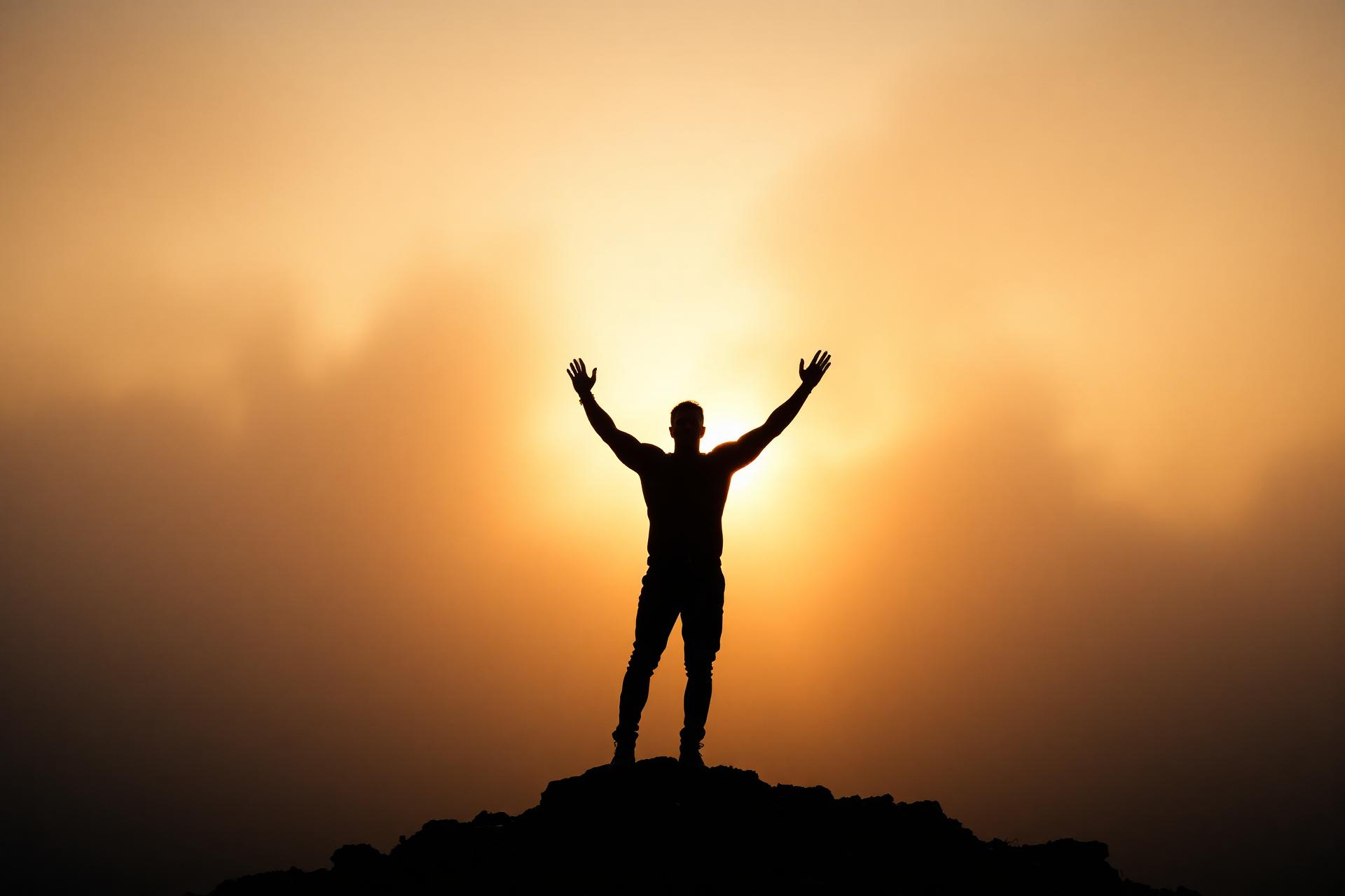 Silhouette of a man on a mountain at sunrise